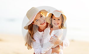 Happy family at beach. mother and child daughter hug at sunset