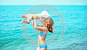 Happy family on the beach. mother throw up baby daughter and pl