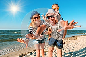 Happy family on the beach. People having fun on summer vacation. Father, mother and child against blue sea and sky background.