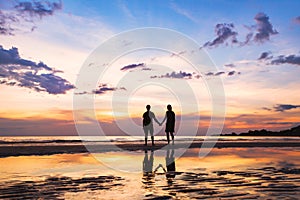 Happy family on the beach, silhouette of couple at sunset, man and woman