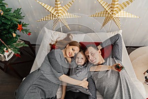 Happy family on bed on a bright Christmas morning. New Year 2019.