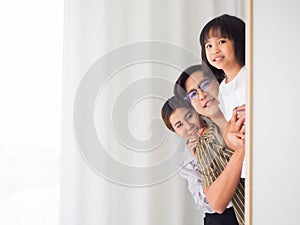 Happy family in bed room concept.father mother and daugther playing hide and seek  behind closet.Childhood, fun, joy, games and