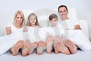 Happy Family In Bed Under Cover Showing Feet photo