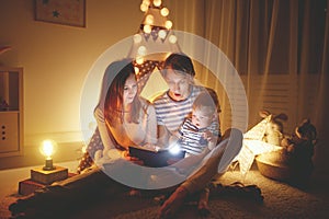 Happy family before bedtime. Mother and father read book to her