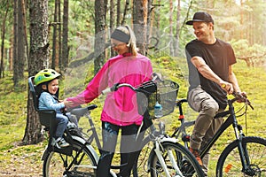 Happy family biking in park with kid in bike child seat. active sports outdoor recreation