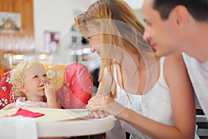 Happy family with blond little girl eating bread