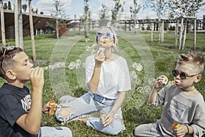 Happy family blowing bubbles outdoors in the park and having fun.