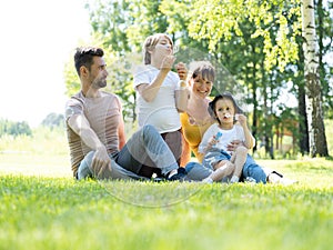 Happy family blowing bubbles in park