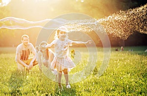 Happy family blowing a bubbles in a spring park