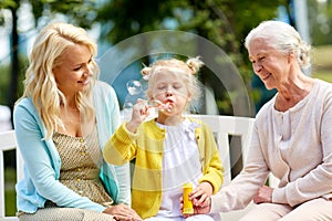 Happy family blowing soap bubbles at park