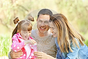 Happy family blowing soap bubbles in park