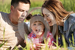 Happy family blowing soap bubbles in park