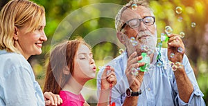 Happy family blowing soap bubbles in the park.