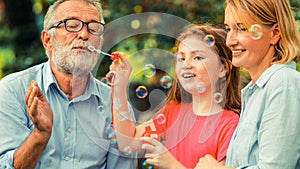 Happy family blowing soap bubbles in the park.