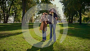 Happy family blowing soap bubbles together standing on green field sunny park.