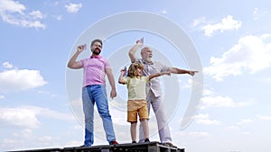 Happy family of boy child with dad and grandad point fingers holding paper planes sky-high, pointing