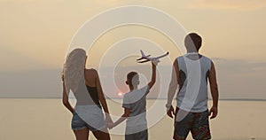 A happy family. The boy with his father and mother with toy airplane at the sunset.