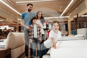 Happy family buys new orthopedic mattress in furniture store. Blissful family choosing mattresses in store.