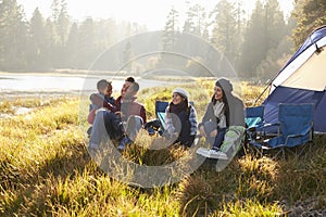 Happy family on a camping trip relaxing by their tent