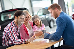 Happy family in car dealership choosing their new car