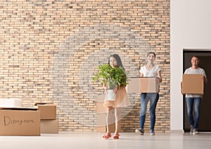 Happy family with cardboard boxes and belongings after moving into new house indoors