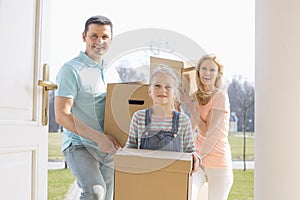 Happy family with cardboard boxes entering new home