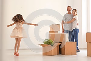 Happy family with cardboard boxes after moving into new house indoors