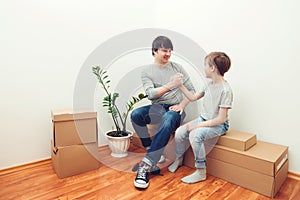 Happy family with cardboard boxes in new house at moving day. Happy dad with son doing handshake