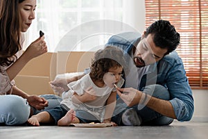 Happy family Caucasian young father with beard feeding cookie snack to his little cute daughter while sitting together on floor