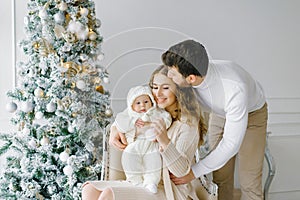 Happy family celebrates Christmas and New Year at home in the living room near the Christmas tree. Family portrait of dad, mom and