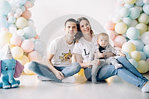 Happy family celebrates first birthday of baby boy among a lot of colorful balloons