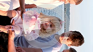 Happy family celebrating little girl's birthday on the seashore mom brings a box with cake girl opens a gift dad mom