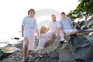 Happy family celebrating little girl's birthday on the seashore mom brings a box with cake girl opens a gift dad mom