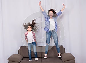 Happy family celebrating mothers day. Happy mother and daughter jumping on sofa. Mother and child enjoying happy mothers