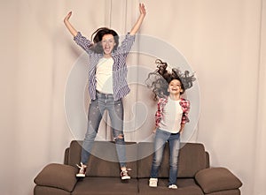 Happy family celebrating mothers day. Happy mother and daughter jumping on sofa. Mother and child enjoying happy mothers