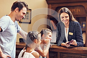 Happy family checking in hotel at reception desk