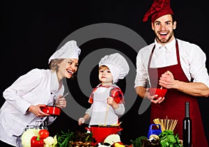 Happy family in chef uniform preparing breakfast, dinner or supper. Healthy food at home. Parents teaching little boy to