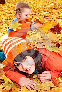 Happy family with child on autumn orange leaves.