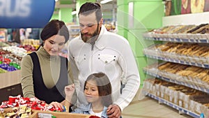 Happy family with a child buying candy and sweets in the supermarket.Slow motion