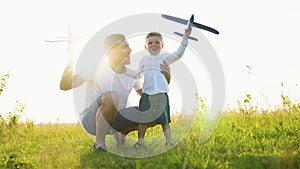 Happy family, child, dad with an airplane play together at sunset in park. Teamwork dad, kid, aviators. Toy plane in