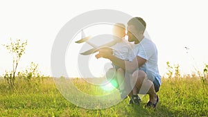 Happy family, child, dad with an airplane play together at sunset in park. Teamwork dad, kid, aviators. Toy plane in