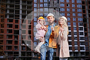 Happy family with child doing thumbs up sign at construction site.
