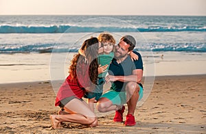 Happy family and child enjoying sunset in the beach. Summer leisure.