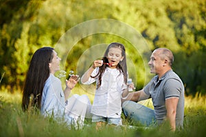 Happy family with child girl blow soap bubbles