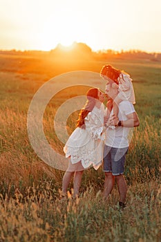 Happy family with child girl walks on meadow at sunset