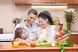 Happy family with child in home kitchen interior with fresh fruits and vegetables, pregnant woman, healthy food concept