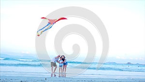 Happy family with child launch a kite, mother father and daughter playing with the older kite in the ocean background in