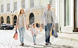 Happy family with child and shopping bags in city