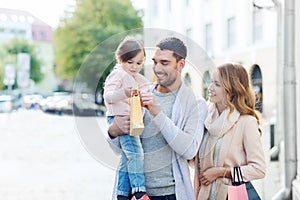 Happy family with child and shopping bags in city