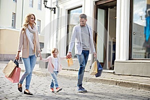Happy family with child and shopping bags in city